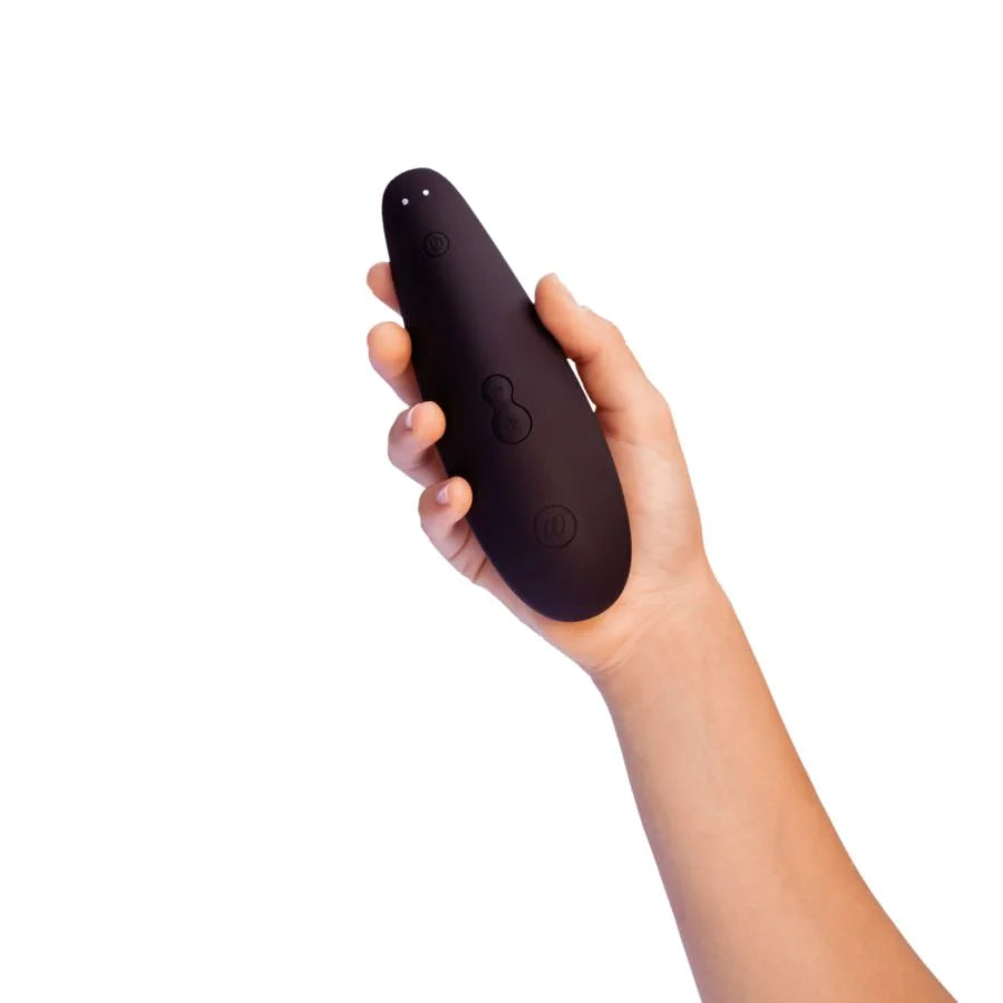 Hand holding a black Womanizer Classic 2 Massager on a white background