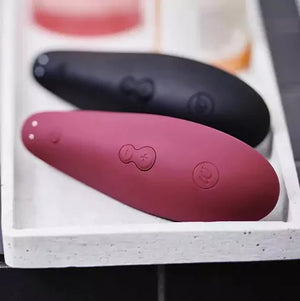 Pink and black silicone Womanizer Classic 2 Massager with control buttons on a white tray.
